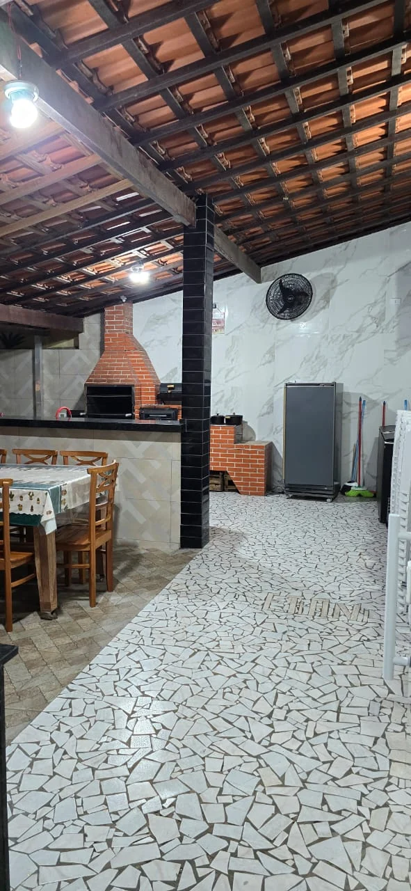Área coberta com churrasqueira e mesa de madeira
