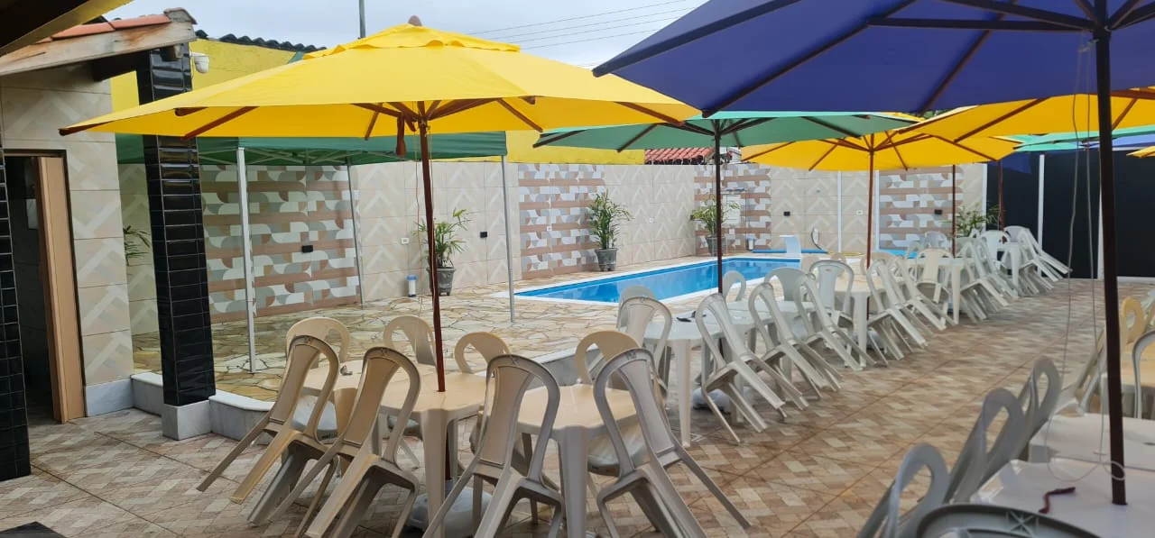 Área externa do Lar dos Sonhos com mesas, guarda-sóis e piscina